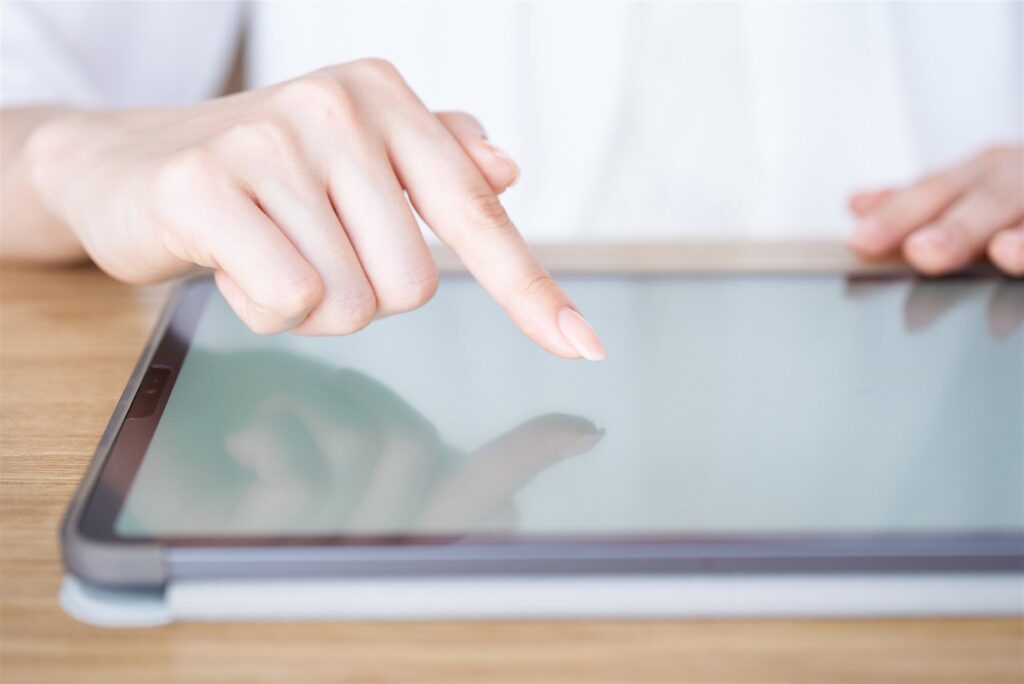 机に置いたタブレットを指で操作する手