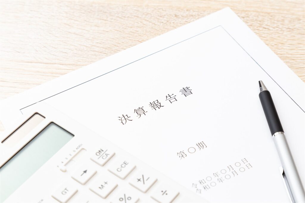 机の上の決算報告書と電卓とペン