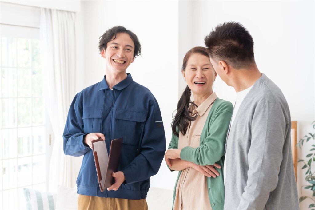 書類のファイルを持つ作業着の担当者と話す夫婦