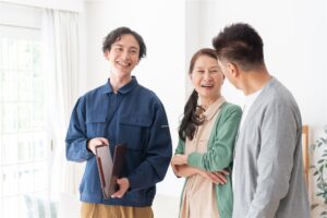 書類のファイルを持つ作業着の担当者と話す夫婦