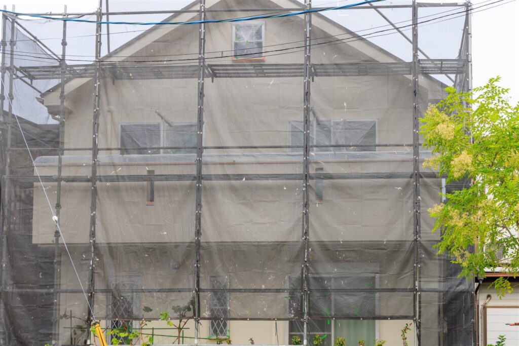 外壁塗装の足場とネットに囲まれた2階建ての住宅