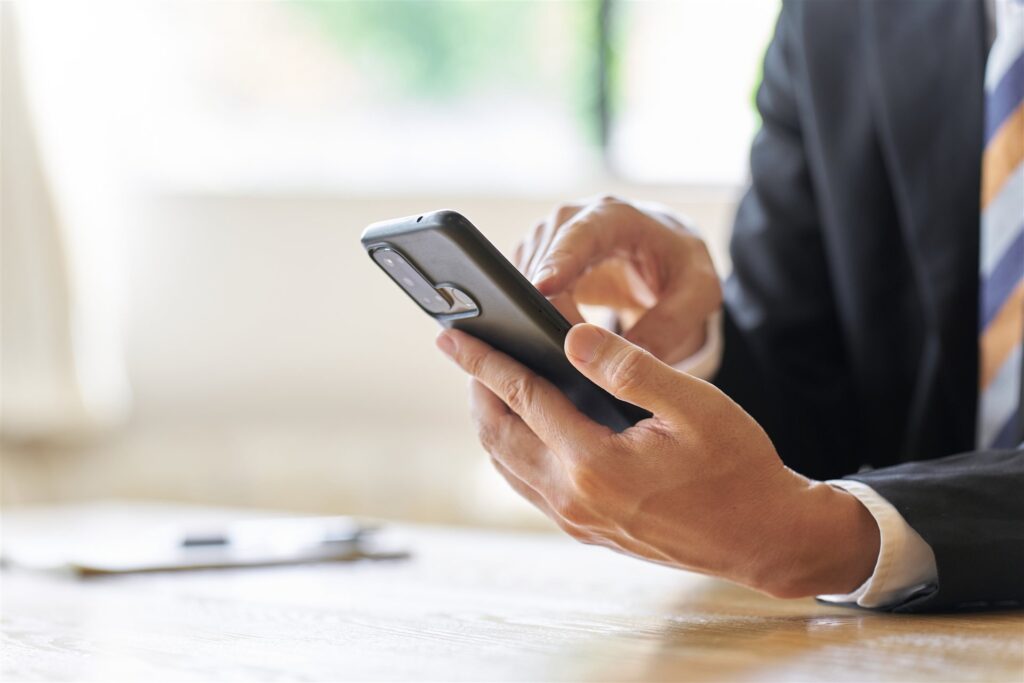 スマートフォンを操作するスーツ姿の人の手元