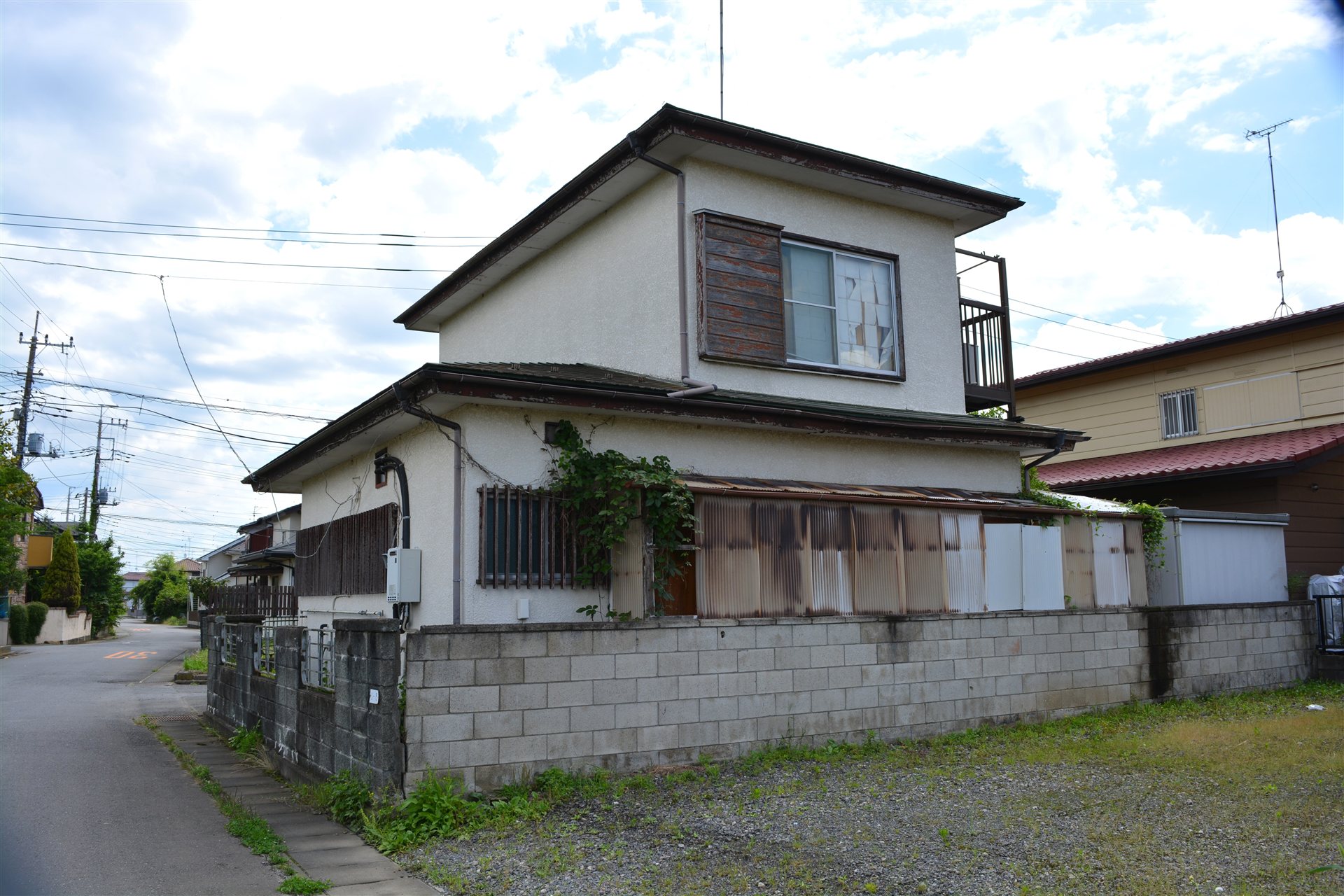 ブロック塀に囲まれた古い2階建ての一戸建て