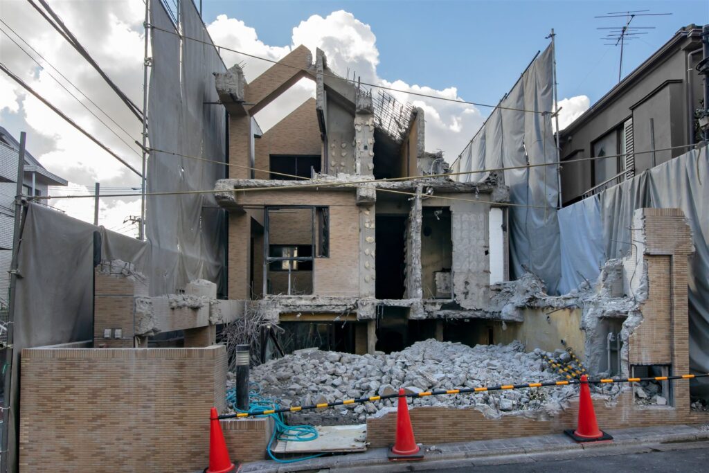 取り壊し中の住宅とがれきの前の三角コーン