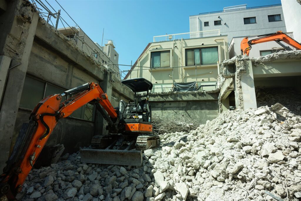 コンクリートの建物の解体とオレンジの重機