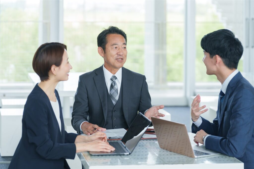 ノートパソコンを前に話し合う3人